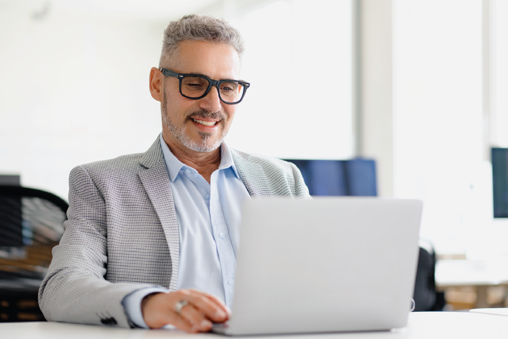 A men smiling in front of his laptop.