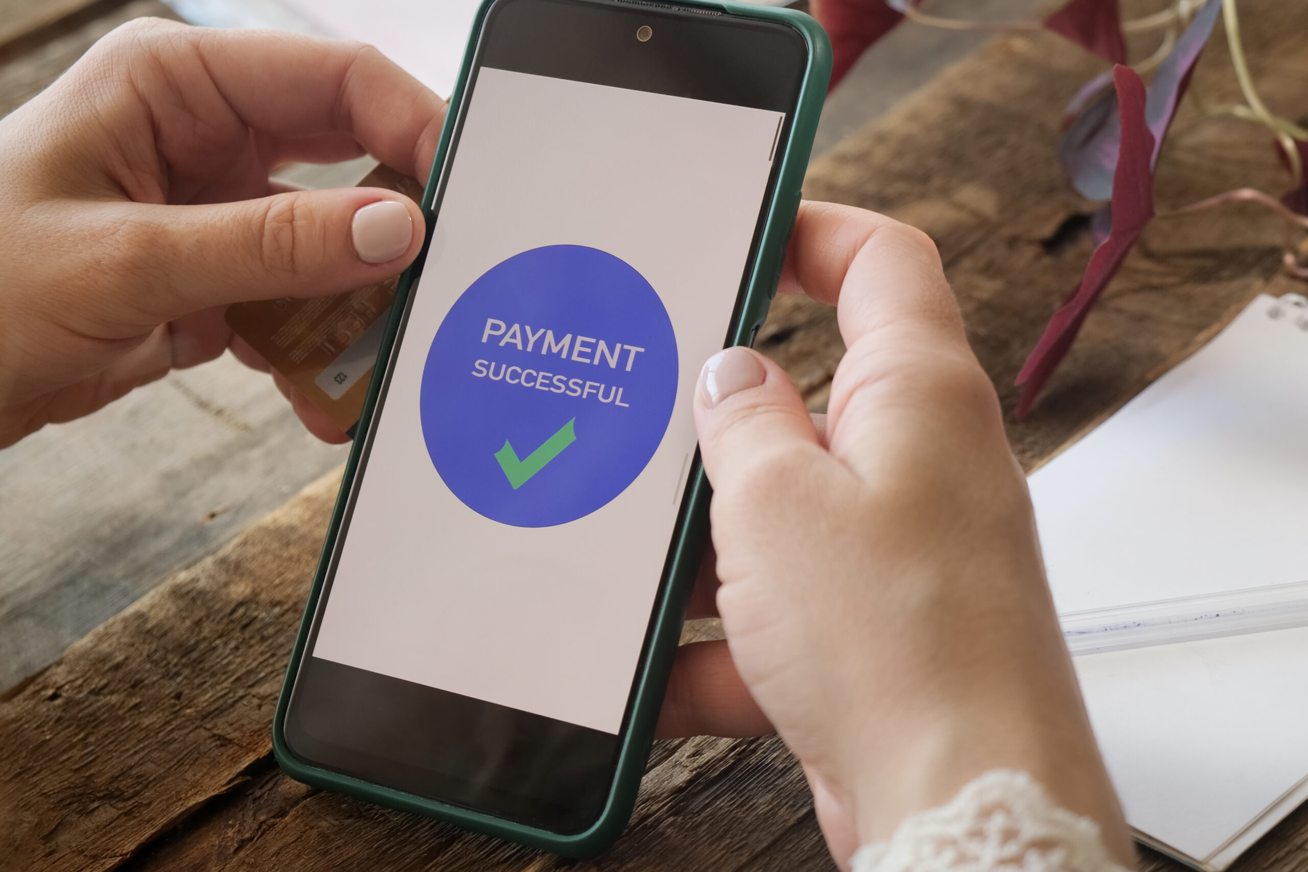 A woman holding a phone showing a "Payment Successful" message on the screen.